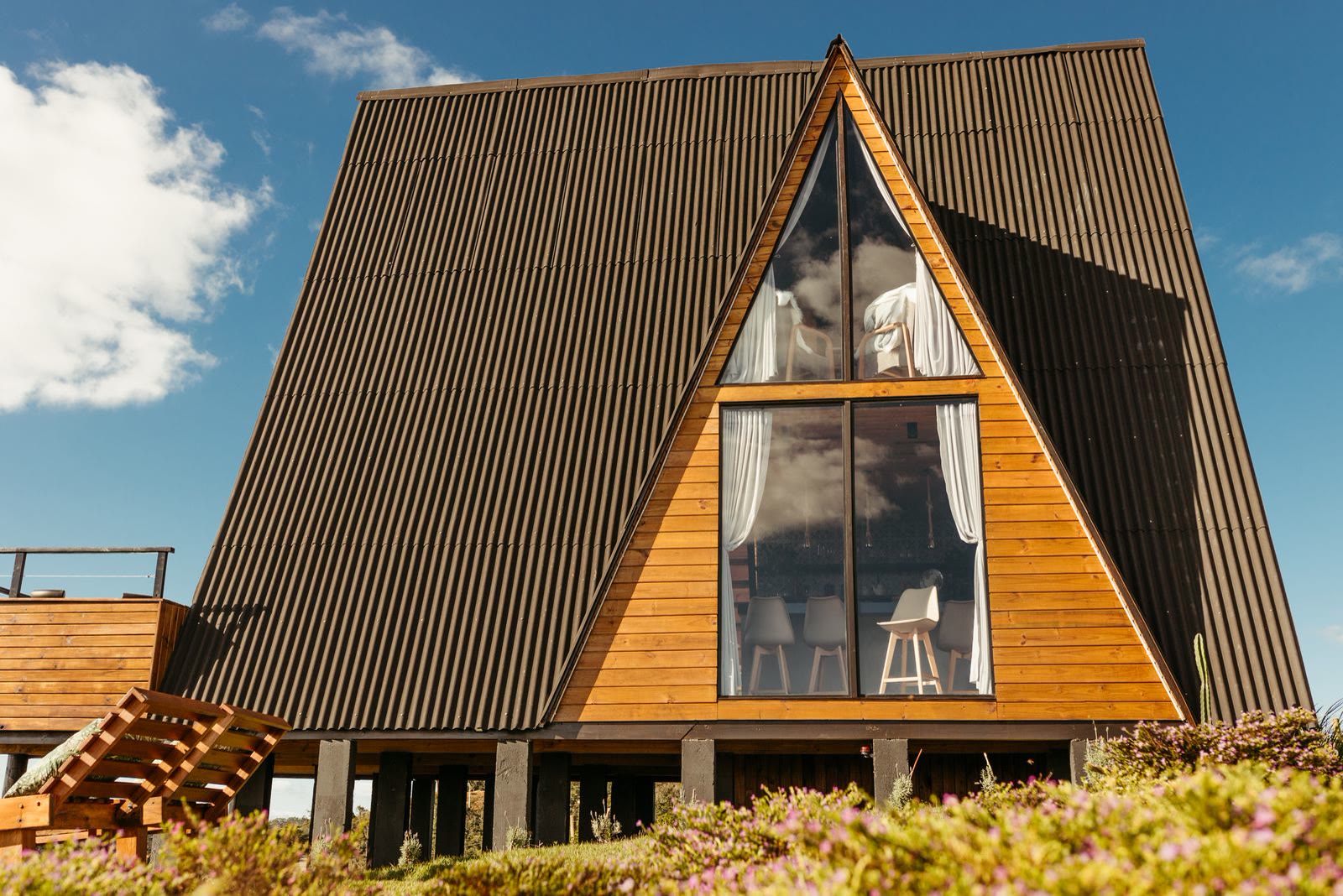 Chalé A-frame com fachada de vidro sobre pilotis