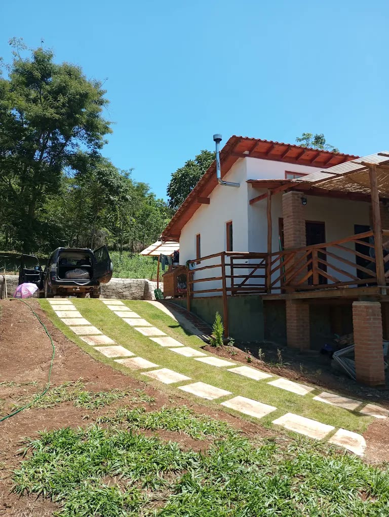 Chalé branco com varanda de madeira e caminho de pedra