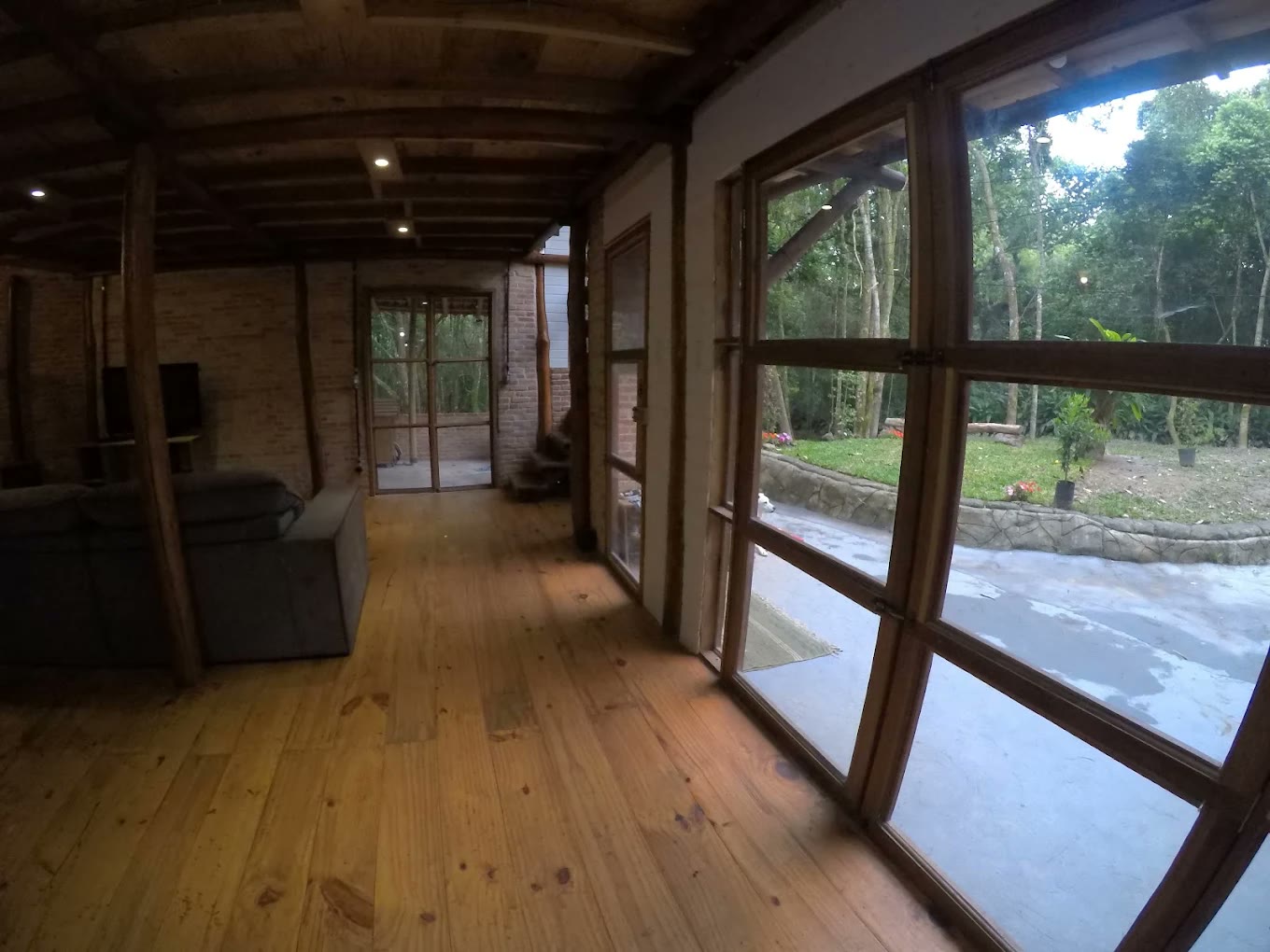Sala com piso de madeira e janelas grandes para a mata